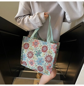 Detail of mint green tote bag featuring colorful sunflower embroidery and wide handles