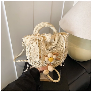 Détail d'un sac en paille tissée avec nœud en dentelle et fleurs en 3D