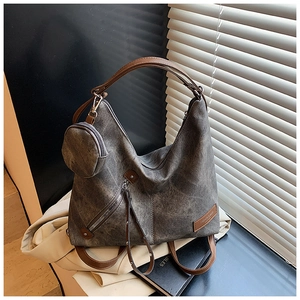 Close-up of gray textured tote bag with side zipper pocket and round pendant purse