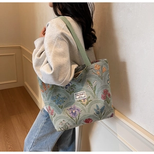 Detail of light green floral canvas tote bag with woven handles and brand label