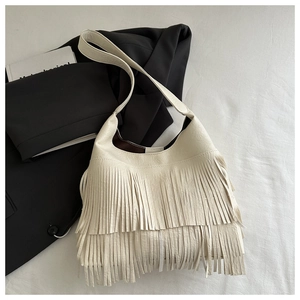 Detailed view of a creamy white hobo bag featuring dense fringe tassels on white fabric