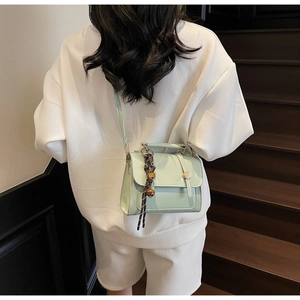 Mint green leather crossbody bag shown on a model on stairs for a stylish look