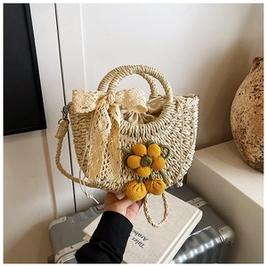 Détail du sac à main en paille tressée avec breloque fleur au crochet et nœud en dentelle