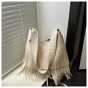 Detail of cream tassel shoulder bag featuring soft faux leather texture and boho fringe