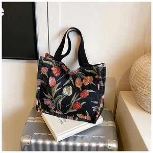 Dettaglio di borsa tote vintage con ricami di tulipani su una valigia argentata