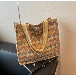 Detailed close-up of woven tote bag featuring colorful geometric patterns and beige straps