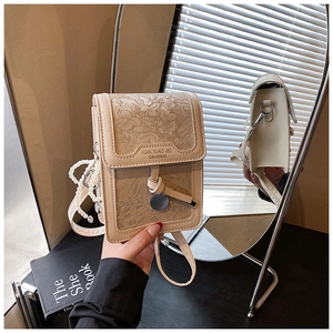 Detail of cream crossbody bag featuring floral embossing and stylish pearl chain strap