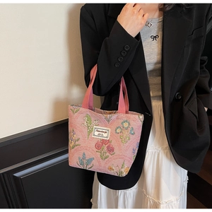 Close-up of pink floral tote bag with brand label worn by model in street style