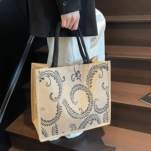 Detailed close-up of textured linen tote bag featuring elegant black floral patterns