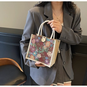 Detailed close-up of a floral tapestry linen tote bag with woven rope handles and a large button