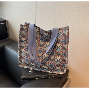 Detail of bohemian geometric woven tote bag with colorful diamond patterns on black sofa
