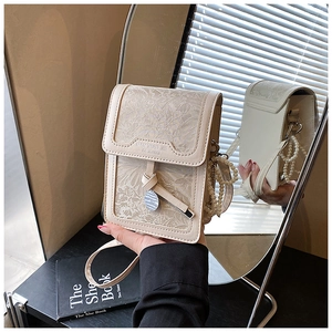 Close-up of cream floral jacquard phone bag with pearl chain and silver pendant detail