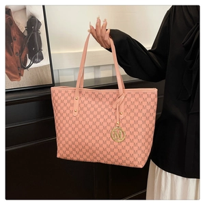 Detailed view of pink monogram tote bag with gold M-logo pendant and premium metal hardware