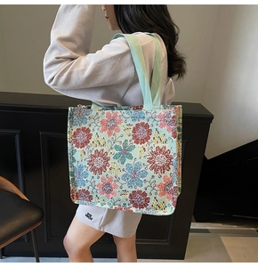 Detailed side view of ethnic floral tote bag with green wide woven straps on shoulder