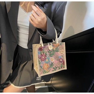 Detail of floral tapestry pattern and woven rope handles on a mini linen lunch bag
