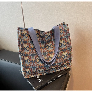 Detail of colorful geometric woven pattern and blue straps on a large tote bag