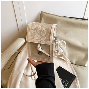 Detail of light beige crossbody bag featuring embossed floral patterns and pearl charm