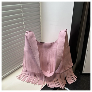 Close-up of light pink crossbody bag featuring long tassels and lychee grain texture