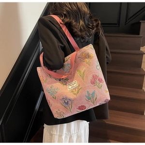 Close-up of pink floral jacquard canvas tote bag with woven handles and brand label