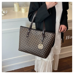Close-up of deep brown tote bag with all-over M-letter print and gold metal charm