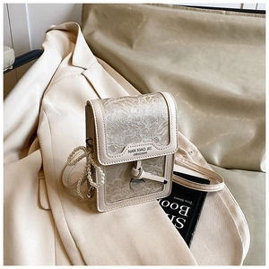 Detail of beige square bag featuring delicate floral lace textures and pearl handle beads