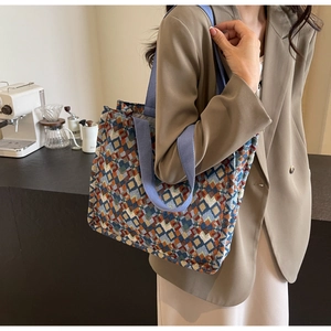 Detail of bohemian tote bag featuring multicolor woven geometric diamond texture and blue strap
