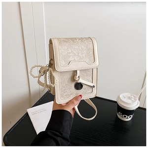 Detail of floral jacquard phone bag featuring pearl charm and embossed logo detail