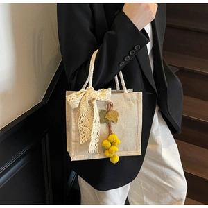Detail of vintage linen handbag with lace bow and plush yellow fruit charm decor