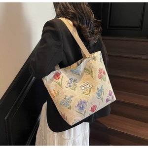 Detail of vintage floral jacquard tote bag with wide strap on model's shoulder