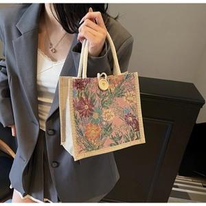 Detailed view of floral jacquard tote bag with braided handles and wooden button closure