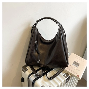 Detail of dark brown tote bag with zipper tassel and dual straps for shoulder or backpack use