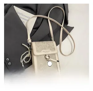 Detail of cream crossbody phone bag featuring floral embossing and elegant pearl chain strap