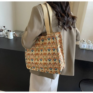 Detailed view of an oversized jacquard tote bag with geometric patterns worn by a model