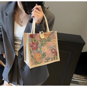 Detail of floral embroidery on jute handbag with white rope handle and wooden button