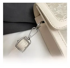 Detailed close-up of silver metal hardware hook and beige leather strap on crossbody bag