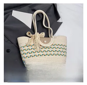 Close-up of woven straw tote bag featuring contrast stripes and a large pearl buckle