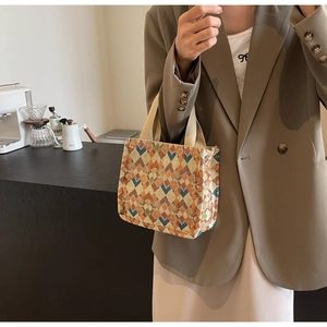 Detail of bohemian geometric tote bag held by model in a cozy urban coffee shop setting