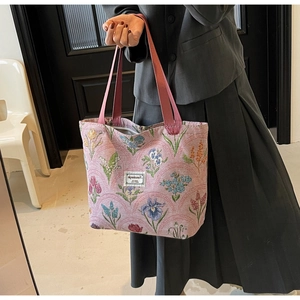 Detail of pink floral tapestry tote bag with tulip patterns and woven brand label