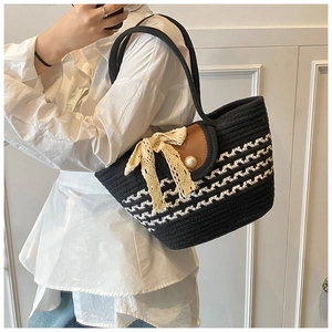 Detail of woven tote bag featuring monochrome wave pattern, lace bow, and pearl closure