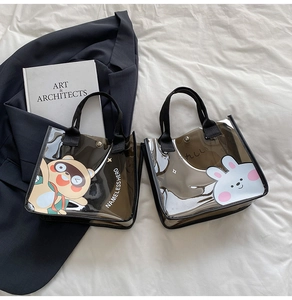 Détail de sacs en PVC transparent avec motifs cartoon et poignées en tissu noir