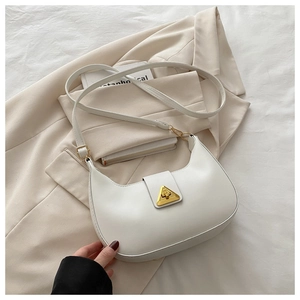 Close-up of a white crescent shoulder bag featuring a gold triangular metal buckle detail