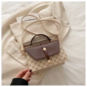 Close-up of small crossbody bag with clover pattern and gold rotating buckle detail
