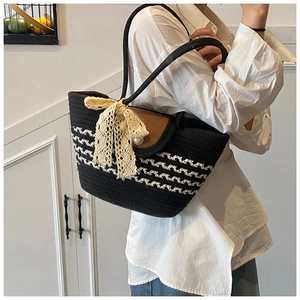 Detail of woven tote featuring leather flap, pearl closure and beige lace bow accessory