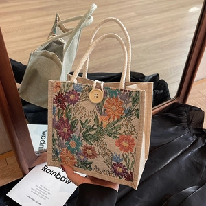 Floral embroidered linen lunch bag with braided rope handles and wooden button closure