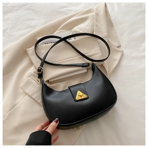 Close-up of black crescent shoulder bag with gold triangular buckle on beige blazer