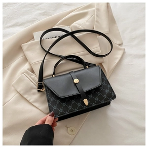 Detail of black crossbody bag featuring grey geometric pattern and gold circular hardware