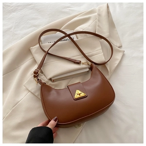 Detail view of brown crescent shoulder bag with matte leather and golden triangle clasp