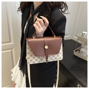 Detail of vintage brown leather flap and monogram crossbody bag held by a model