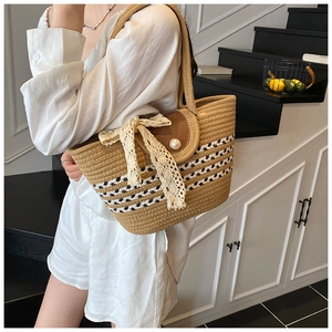 Detail of woven straw tote with pearl buckle and lace bow on a textured handle
