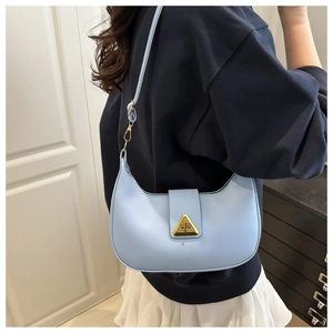 Detail of light blue crescent bag with golden triangle clasp and adjustable strap
